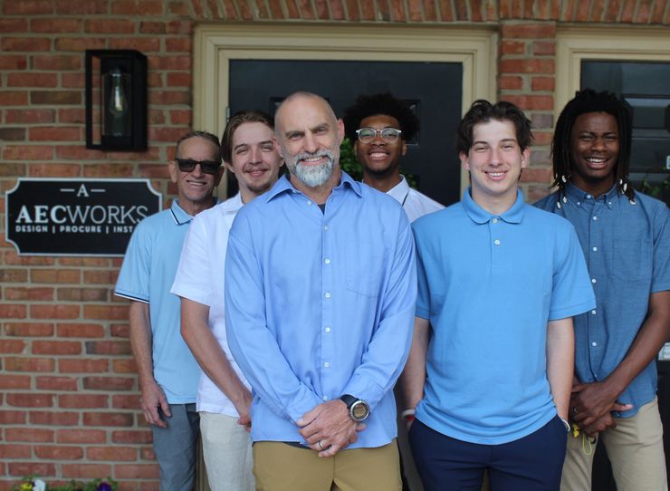 Group photo of six men in front of a brick building.